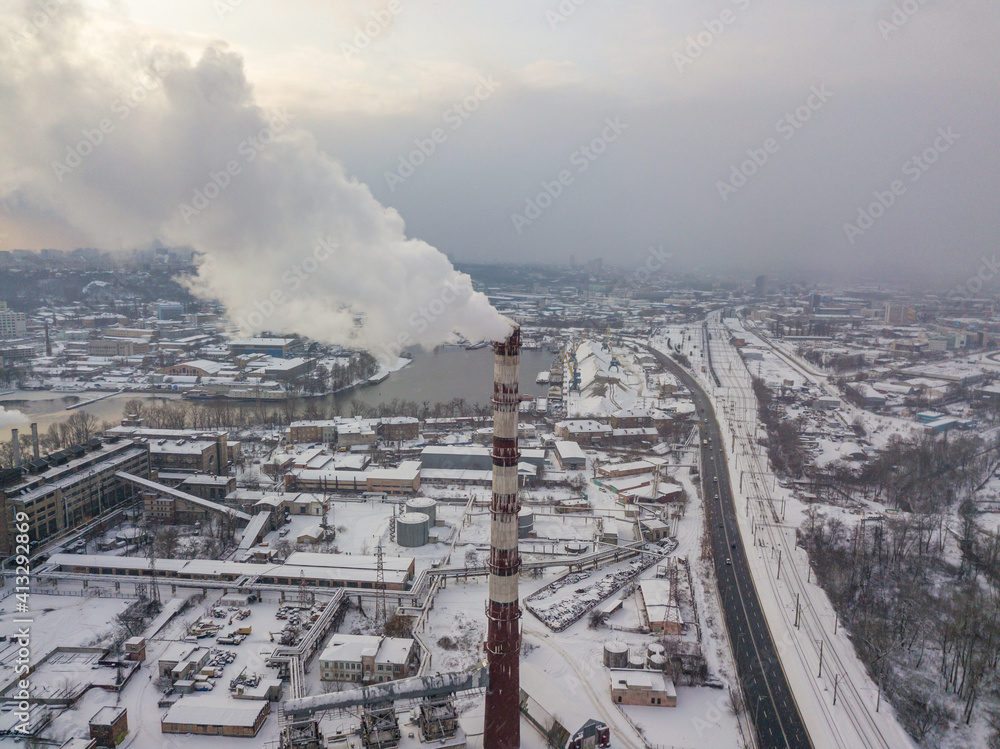 The flue pipe of the power plant. Aerial drone view. Winter snowy evening.