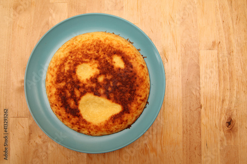 Cottage cheese casserole on a blue plate on a wooden background. muzzle, mem, funny picture