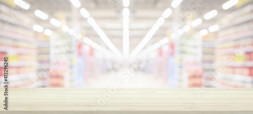 Wood table top with supermarket grocery store blurred background with bokeh light for product display © Kwangmoozaa