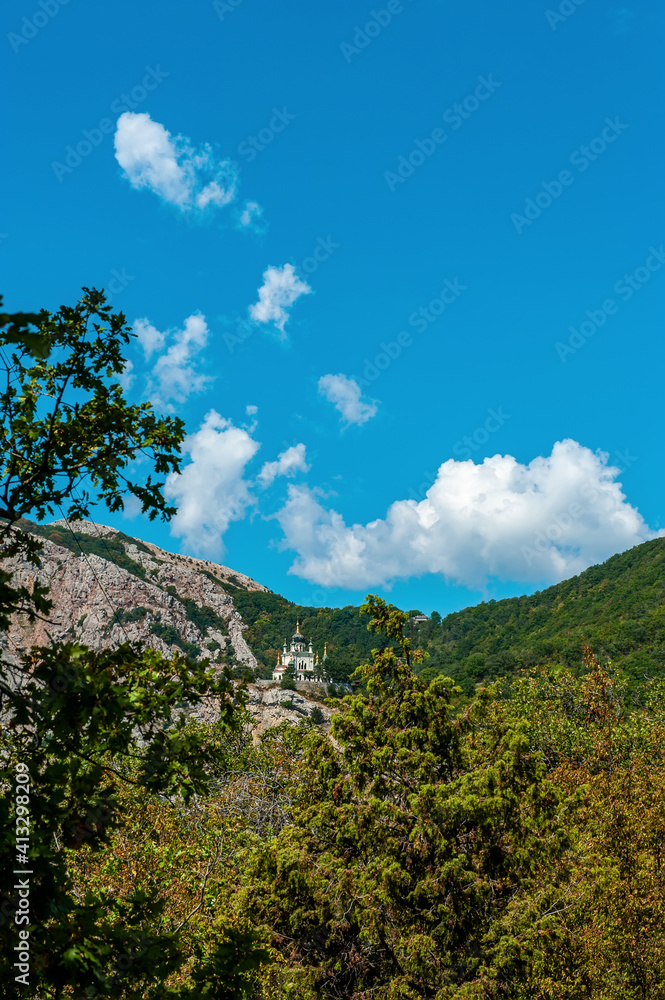 Summer sunny view of the Crimean road in the mountains. Beautiful mountain landscape of the Crimean Peninsula. In the distance, the Church of the Resurrection of Christ in Foros