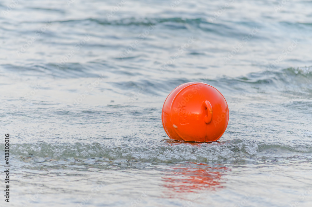 Naklejka premium A red buoy on the surface of the water on the beach in Pefkochori, Greece