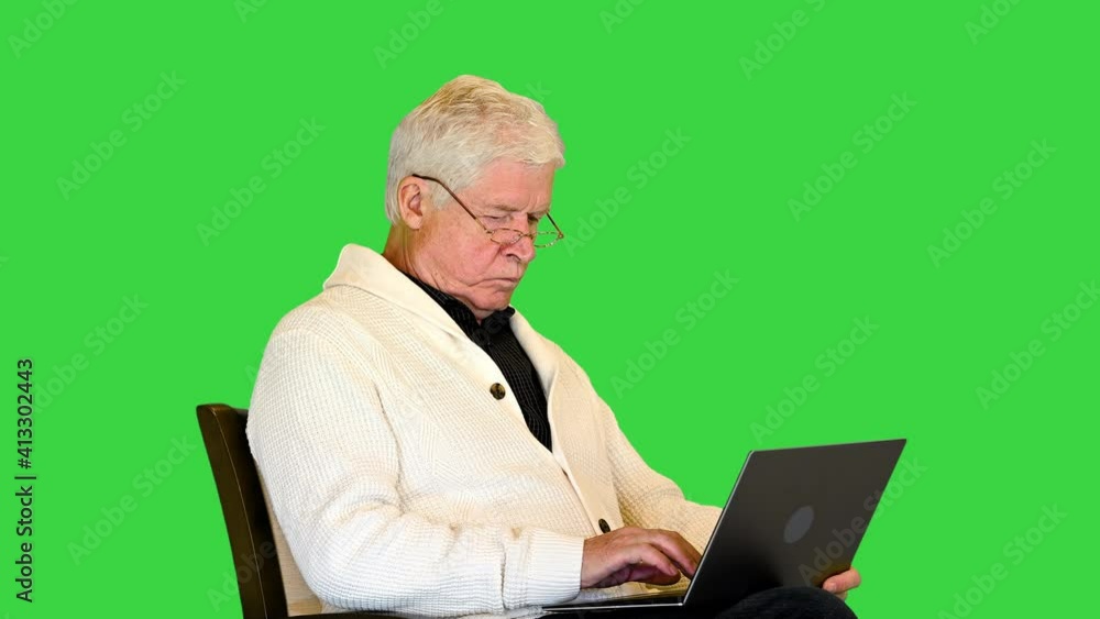 Old man sitting in armchair using laptop computer on a Green Screen, Chroma Key. Old man sitting in armchair using laptop computer on a Green Screen, Chroma Key.