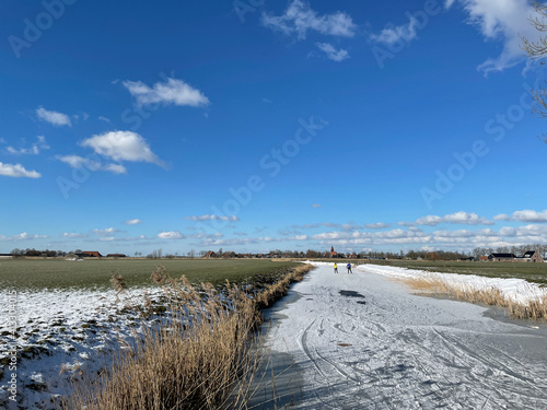 Couple ice skating on a frozen canal in Friesland