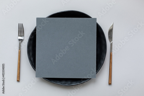Абстрактный фон в стиле минимализм. На черной тарелке серый квадратный лист бумаги.