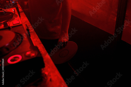 Parcial view of a deejay holding a vinyl record in his hand photo