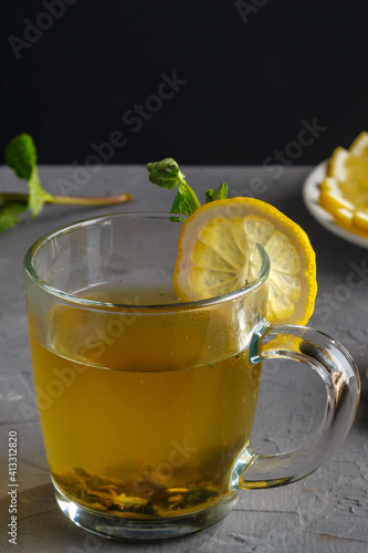 vitamin ginger drink with honey mint and lemon in a glass cup on a concrete background.