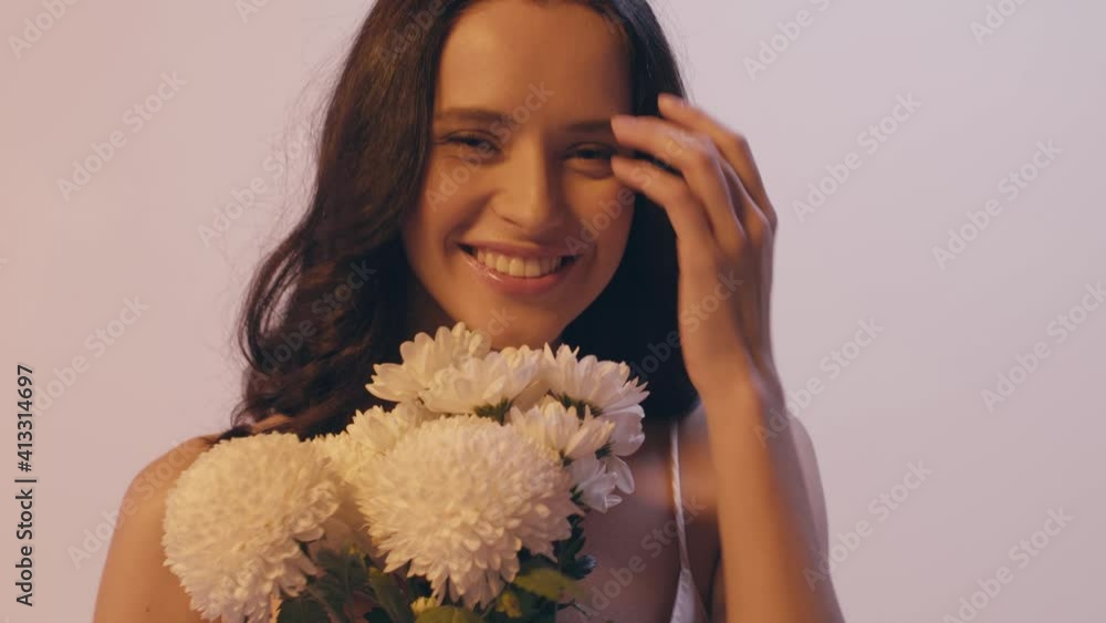 young woman smelling bouquet of white flowers and smiling isolated on grey young woman smelling bouquet of white flowers and smiling isolated on grey