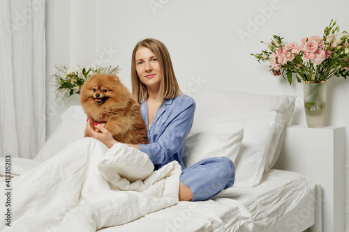 Beautiful woman with spitz in bedroom
