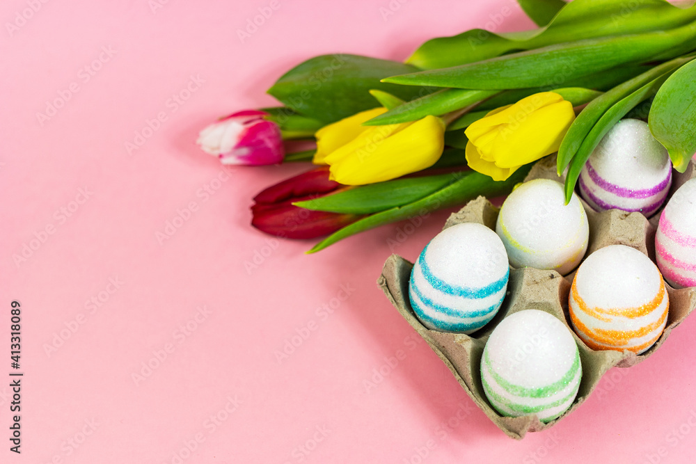 Easter painted eggs with tulips on a pink background. Copy space. Easter celebration concept. Easter painted eggs with tulips on a pink background. Copy space. Easter celebration concept.