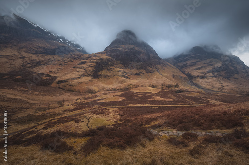 Dark and moody mountain landscape of Glencoe in the Scottish Highlands with the ridges of Beinn Fhada, Gearr Aonach and Aonach Dubh (Three Sisters of Glencoe).
