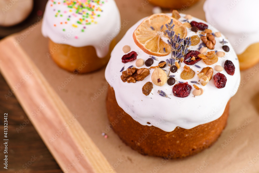 Festive cakes with white glaze, nuts and raisins with Easter eggs on the festive table Festive cakes with white glaze, nuts and raisins with Easter eggs on the festive table