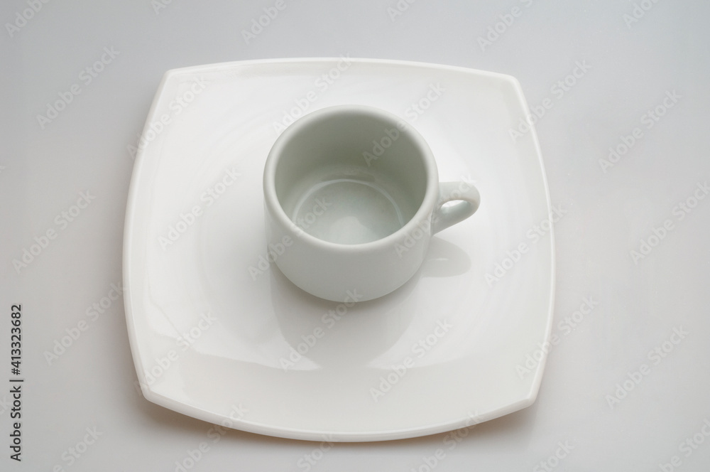 Taza de café sobre un plato. Un único color blanco. Foto de estudio. Taza de café sobre un plato. Un único color blanco. Foto de estudio.