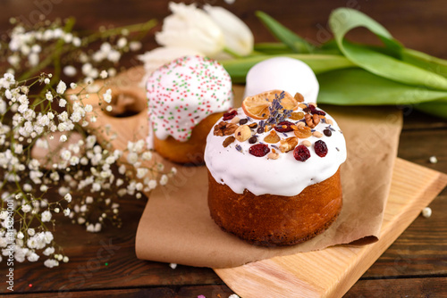 Festive cakes with white glaze, nuts and raisins with Easter eggs on the festive table