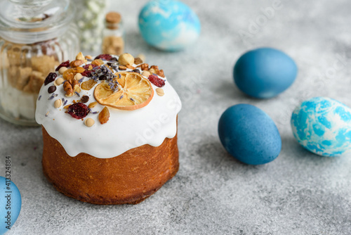 Festive cakes with white glaze, nuts and raisins with Easter eggs on the festive table