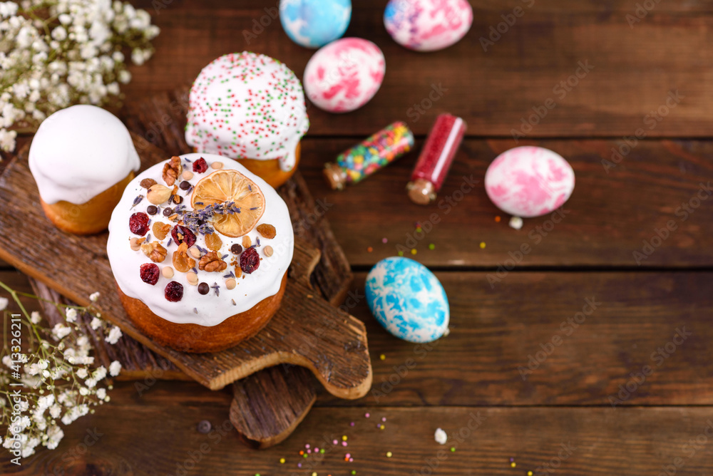 Festive cakes with white glaze, nuts and raisins with Easter eggs on the festive table Festive cakes with white glaze, nuts and raisins with Easter eggs on the festive table