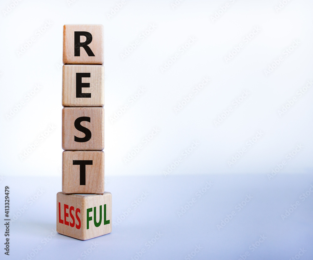 Restless or restful symbol. Turned the wooden cube, changed the word 'restless' to 'restful'. Beautiful white table, white background, copy space. Business and restless or restful concept. Restless or restful symbol. Turned the wooden cube, changed the word 'restless' to 'restful'. Beautiful white table, white background, copy space. Business and restless or restful concept.