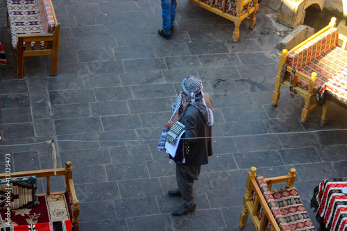 Man with ethnic clothing selling traditional headdress in the courtyard of historic Gumruk Hani, Customs Inn, Customs House in Sanliurfa, Turkey.