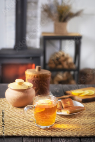 Pancakes with filling and tea with .honey and lemon on a wooden table against the background of a burning fireplace