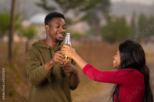 young black man and woman make a toast together when having drinks outdoor