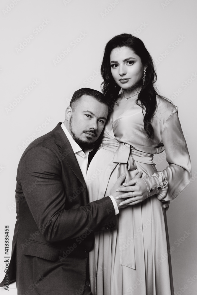 Pregnancy photoshoot of a beautiful couple, future parents in a gray dress and suit Pregnancy photoshoot of a beautiful couple, future parents in a gray dress and suit
