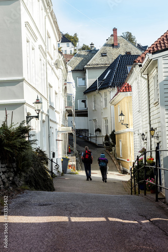 two tourists stroll along a street with white houses