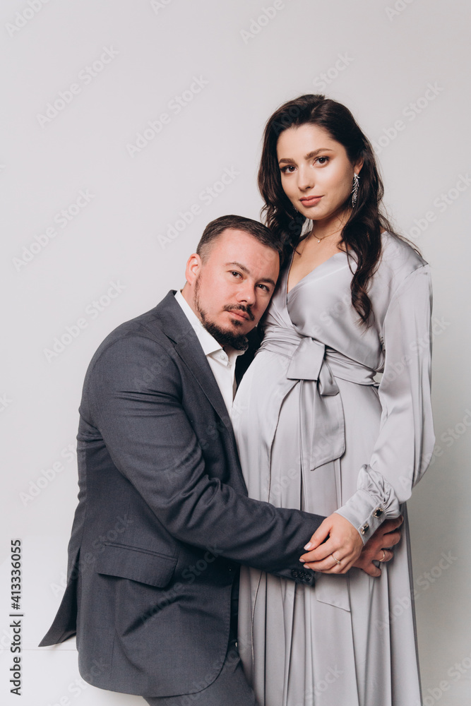 Pregnancy photoshoot of a beautiful couple, future parents in a gray dress and suit Pregnancy photoshoot of a beautiful couple, future parents in a gray dress and suit