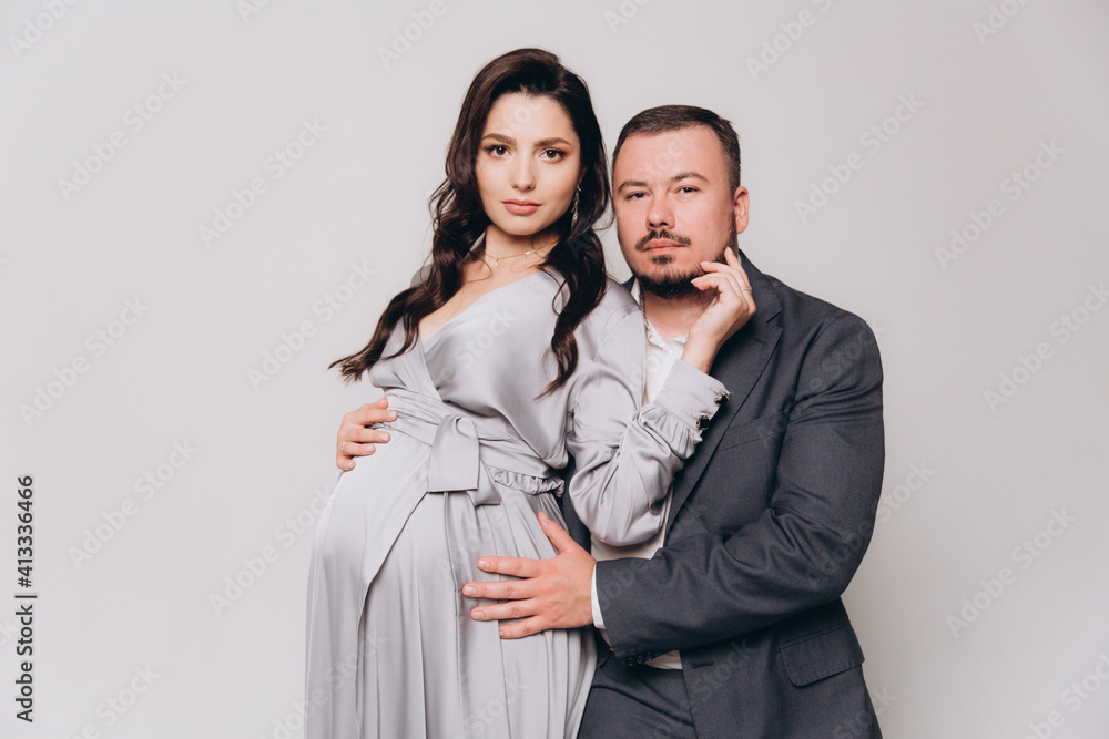 Pregnancy photoshoot of a beautiful couple, future parents in a gray dress and suit Pregnancy photoshoot of a beautiful couple, future parents in a gray dress and suit