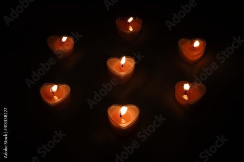 The small table candles in shape of red heart stands on table and fire burns. Romantic and love rendezvous concept.
