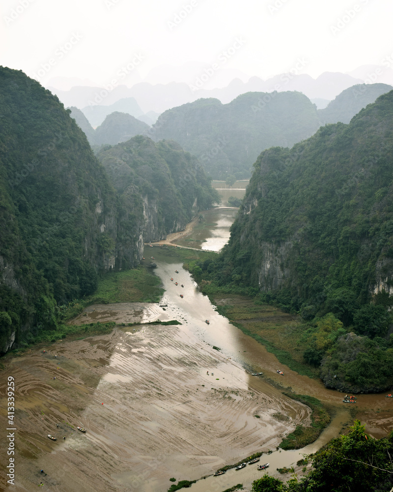 Hang Mua, Vietnam: An epic view, seen from the peak of the Hang Mua Mountain, of a lazy river cutting through limestone karsts, with rice fields being prepared in the winter season