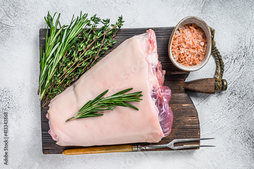 Raw Pork knuckle eisbein for cooking with herbs. White background. Top view photo