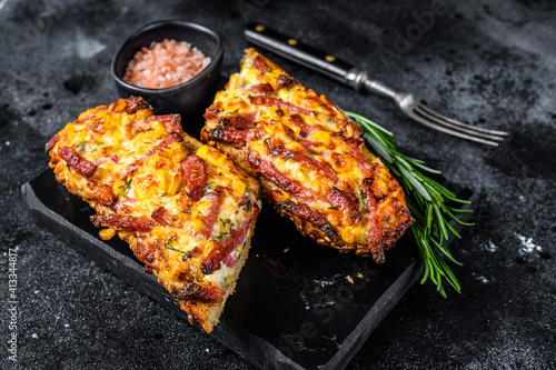 Hot baked open Baguette sandwich with ham, bacon, vegetables and cheese. Black background. Top view
