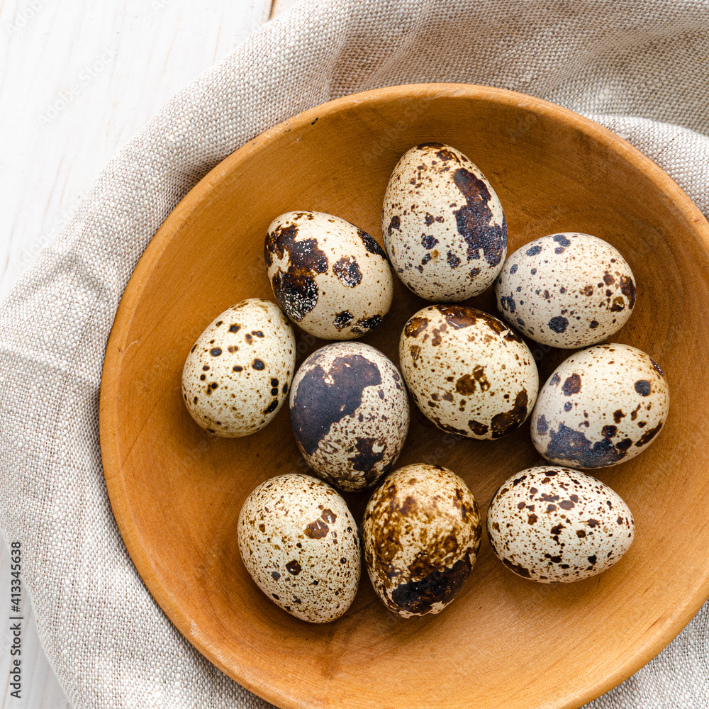 The quail eggs lie on a wooden plate on a white table The quail eggs lie on a wooden plate on a white table