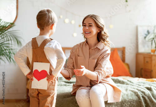 Boy making surprise for mother during holiday celebration photo