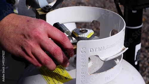 Man hand connection propane natural gas tank valve turning opening to allow fuel to flow into lines. Providing power to camper van life travel trailer heater.