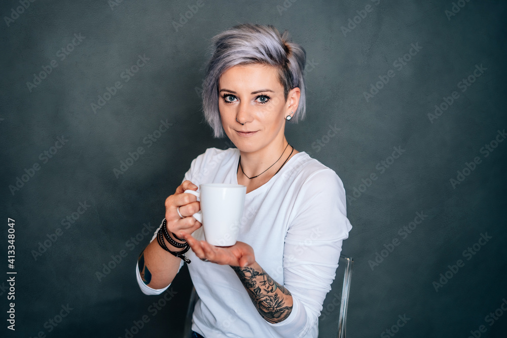 Frau mit Tasse in der Hand Kaffee Tee casual tätowiert weißes Shirt dunkler Hintergrund vintage Style Pause