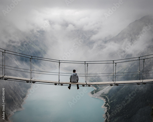 Mann sitzt auf einer Hängebrücke im Zillertal photo