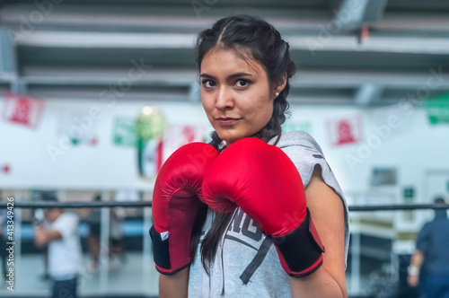 Quadro su tela Young attractive latin woman boxer wearing red gloves training on boxing ring