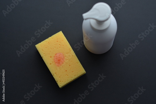 White dispenser bottle whith dish washing liguid and yellow sponge. Copy space. Mockup, minimalistic style. photo