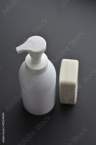 White bottle isolated on black background. Unbrending bottle for mockup. Dishwashing liquid is flowing from bottle.