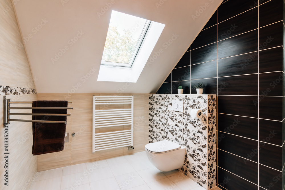 Small attic bathroom with sunroof. The tiling is in brown and beige colors variegated with