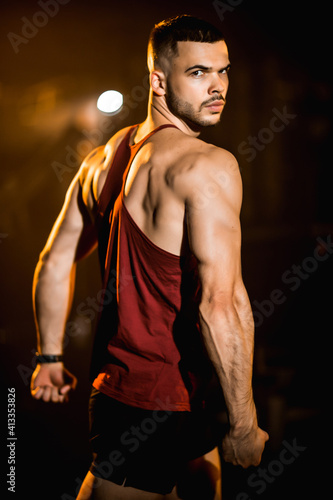 The trainer in the gym, shows his muscles, athletic man.