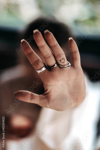 Female hand with silver jewelry and small heart shaped tattoo 