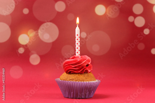 Cupcake with cream and a burning candle for a birthday or other holiday with a shopping plan on a colored background with bokeh lights 