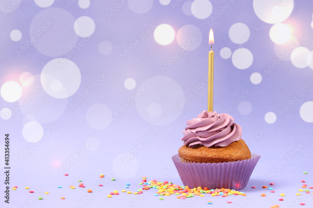 Cupcake with cream and a burning candle for a birthday or other holiday with a shopping plan on a colored background with bokeh lights Cupcake with cream and a burning candle for a birthday or other holiday with a shopping plan on a colored background with bokeh lights