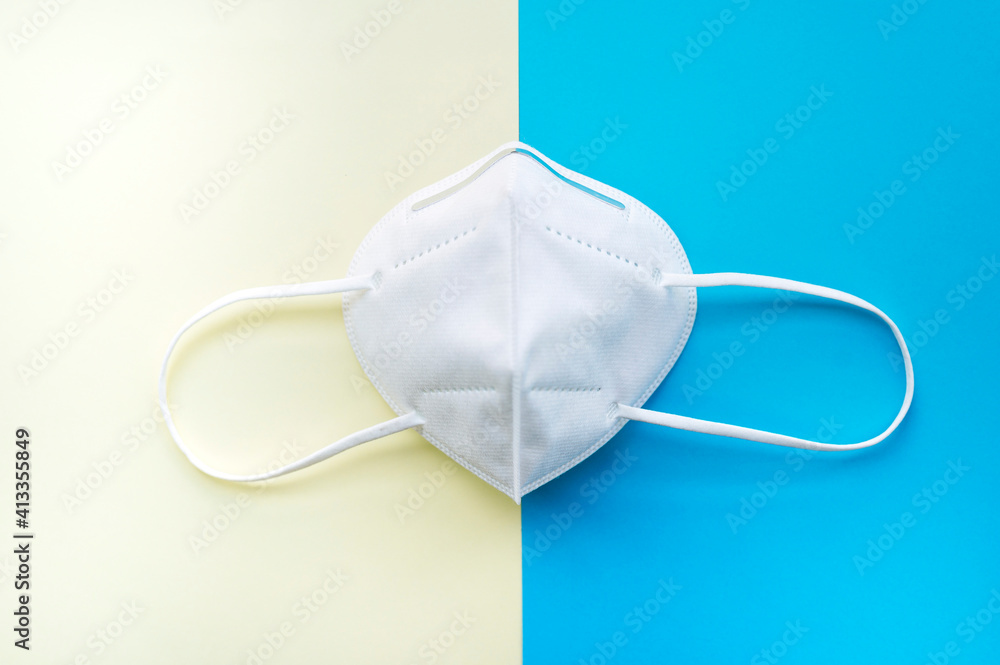 white face mask isolated on a blue and yellow surface white face mask isolated on a blue and yellow surface