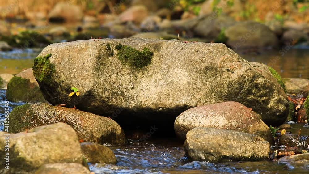 Water running through big stones in water. Close up view mountain stream with stones. Flowing river with blue water. Water running through big stones in water. Close up view mountain stream with stones. Flowing river with blue water.