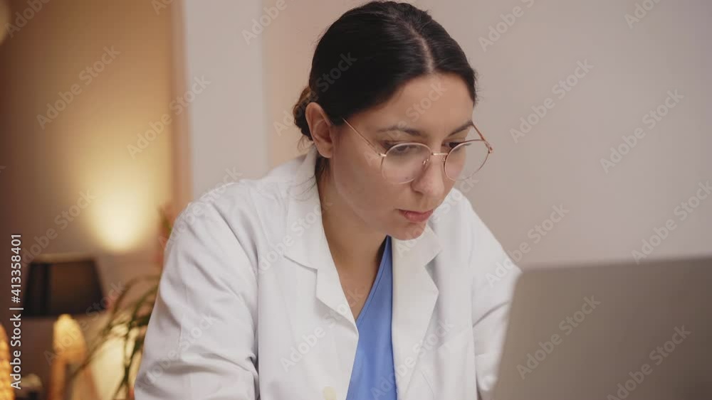 Serious young woman doctor physician wearing white coat using laptop computer. Female professional medic consulting patient distantly in online chat sit at desk in hospital. Serious young woman doctor physician wearing white coat using laptop computer. Female professional medic consulting patient distantly in online chat sit at desk in hospital.