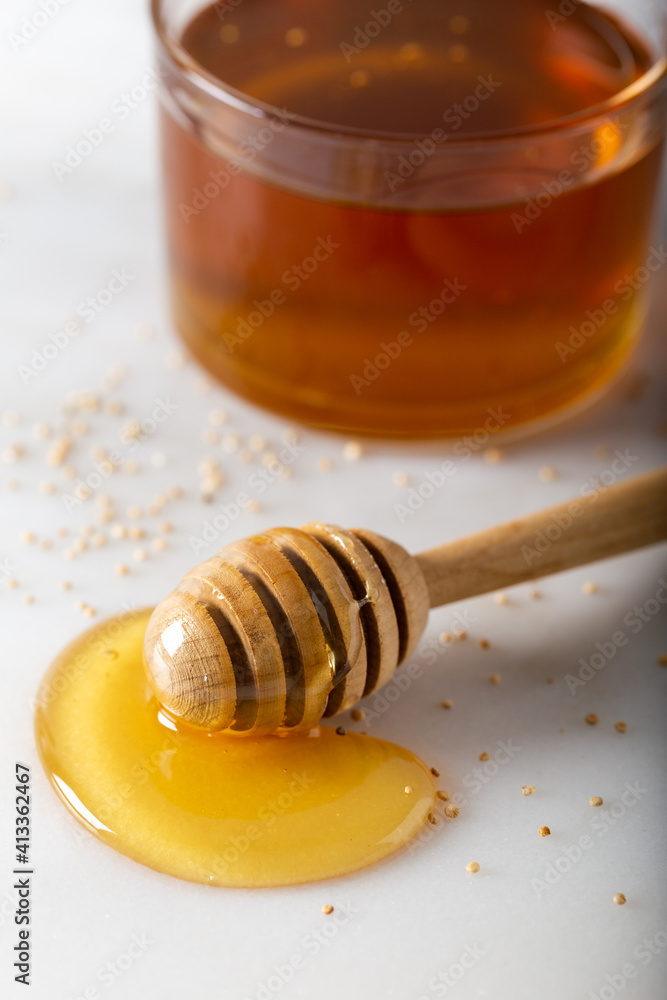 Honey stick with flowing honey and bee pollen granules on the marble background. Honey stick with flowing honey and bee pollen granules on the marble background.