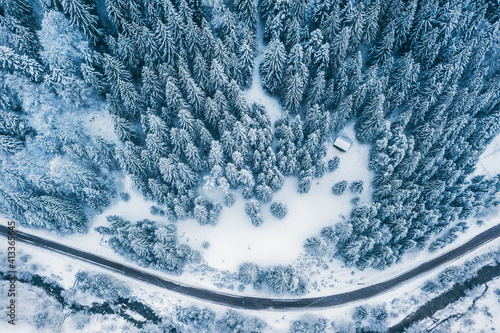 Aerial top view drone shot of the pine and spruce trees forest covered with snow in the Tatra Mountains in Slovakia with a countryside rural road. Transportation and ecology concept image. photo