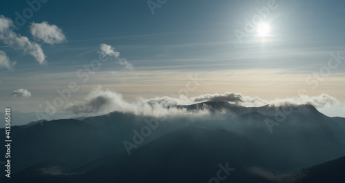 Slovakian Tatry mountain landscape view from Velky Rozsutec mountain. Sun is going down at evening and light up a clouds over the peaks.